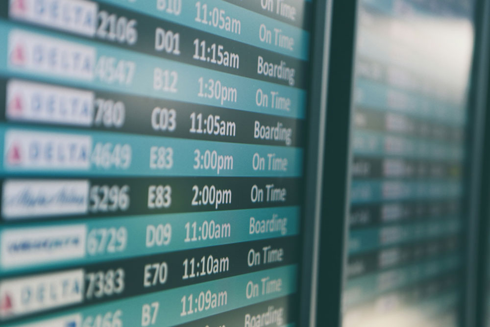 Close-up of a departure information board displaying flight times and statuses at an airport.