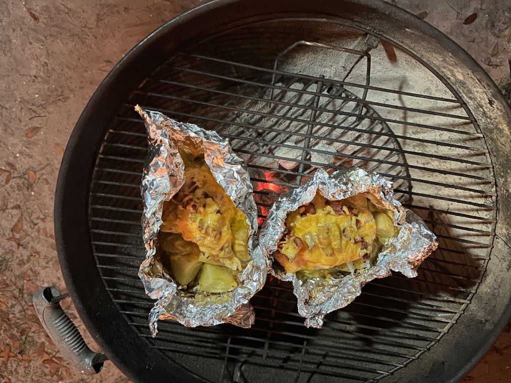 Chicken Bacon Ranch with Potatoes in foil packets cooking on a charcoal grill