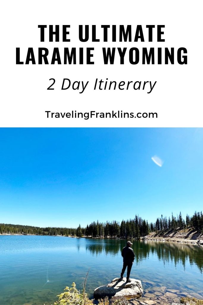 Pinterest pin graphic titled 'THE ULTIMATE LARAMIE WYOMING 2 Day Itinerary' from TravelingFranklins.com, with a background image of a person standing by a tranquil lake