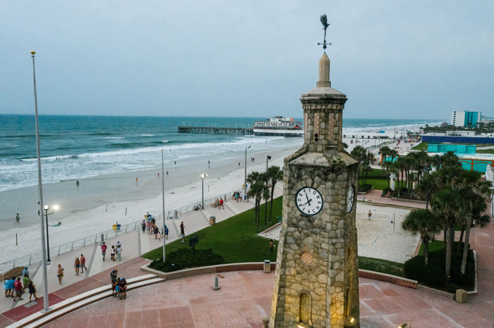 A captivating view of Daytona Beach with a unique clock tower in the foreground, as beachgoers enjoy the expansive sandy shore.