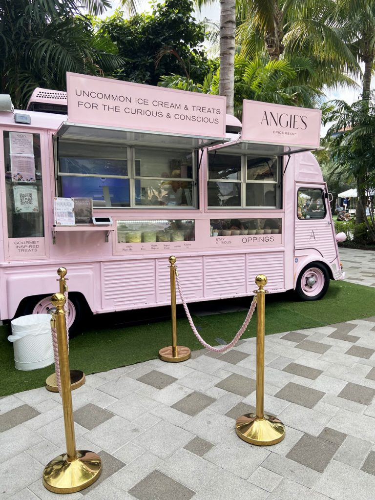Angie's pink food truck offering unique ice cream and treats, with a tropical backdrop in West Palm Beach at The Square