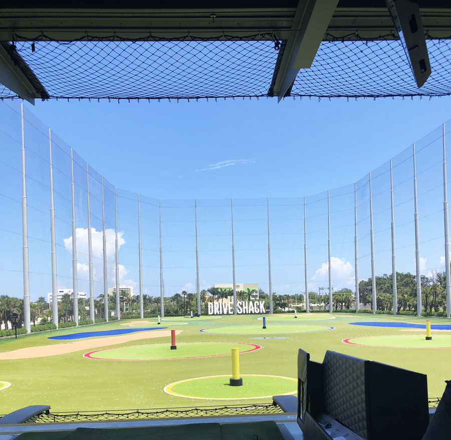 Drive Shack golf entertainment venue with a wide open green field and targets, clear blue skies in West Palm Beach.