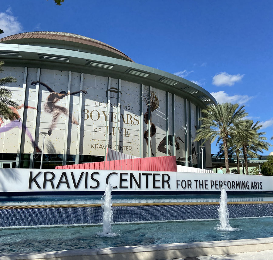 Kravis Center for the Performing Arts building front with celebratory banners and a water fountain, West Palm Beach.