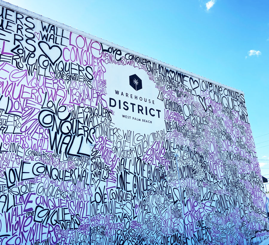 Eye-catching mural with purple and white love-themed graffiti in West Palm Beach's Warehouse District.