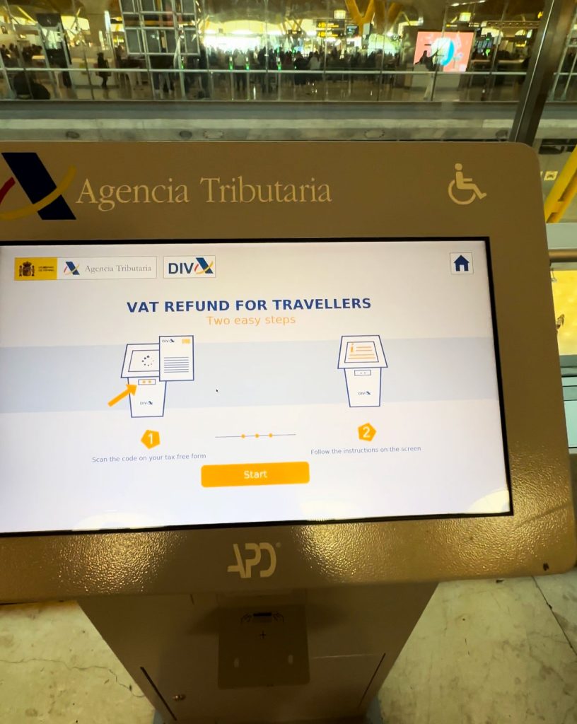 Close-up of a VAT refund kiosk screen with instructions for scanning a tax-free form. The screen is part of the Agencia Tributaria system in an airport.