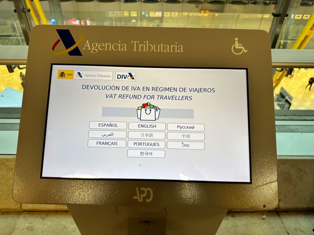 A VAT refund kiosk screen displaying language options including Spanish, English, and French. The screen is part of the Agencia Tributaria (Tax Agency) system in an airport.